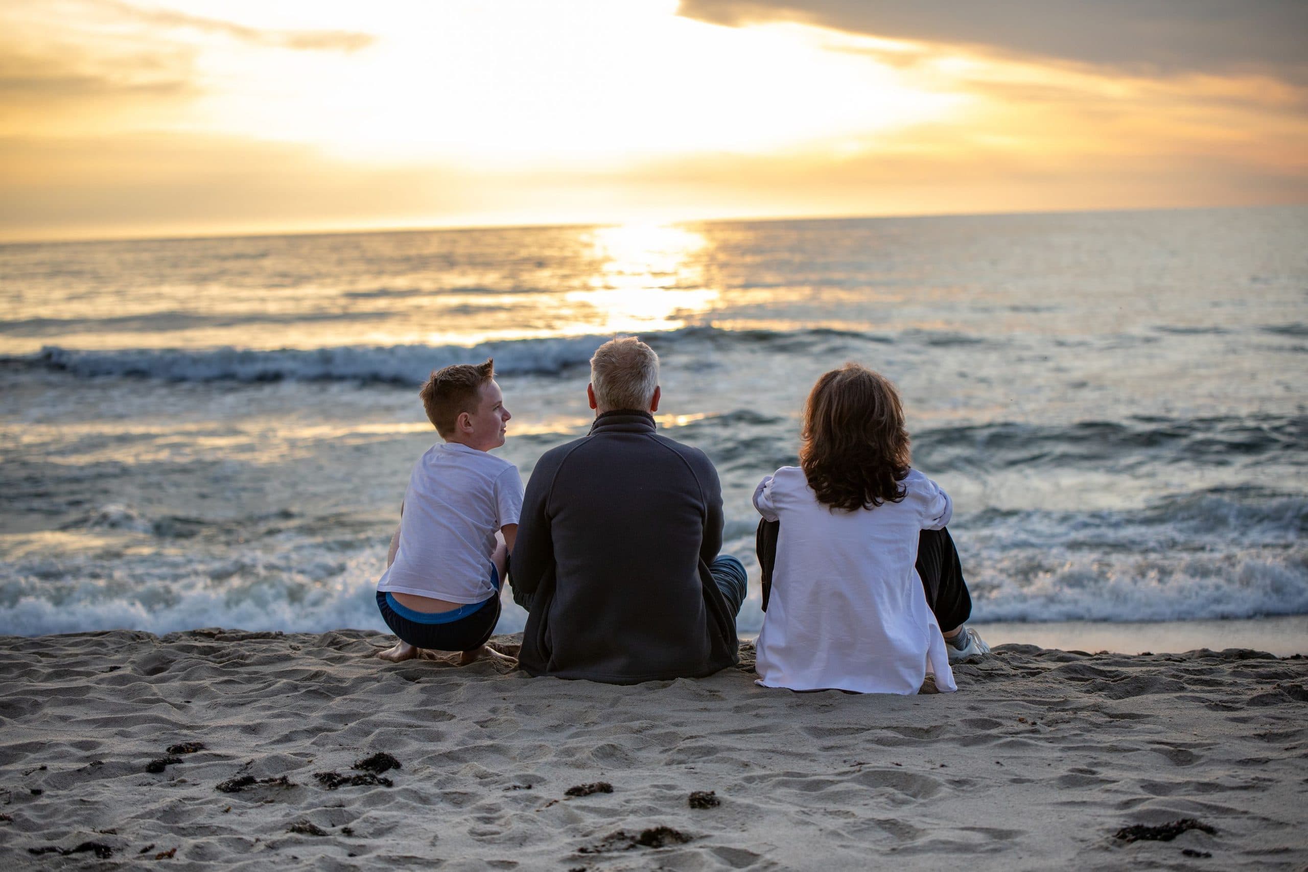 A family sitting together looking out over mountains at sunset